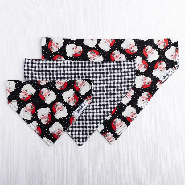Reversible dog bandana with Santa heads on front and black and white houndstooth on back.