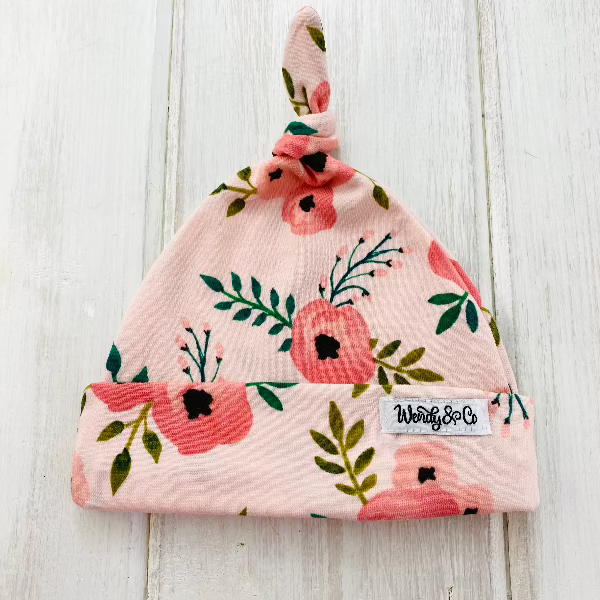 Peach floral newborn beanie with top knot.