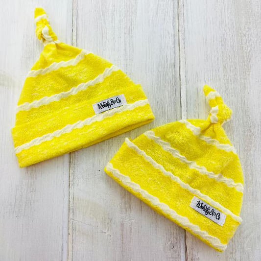Bright yellow infant beanie with white textured stripe.