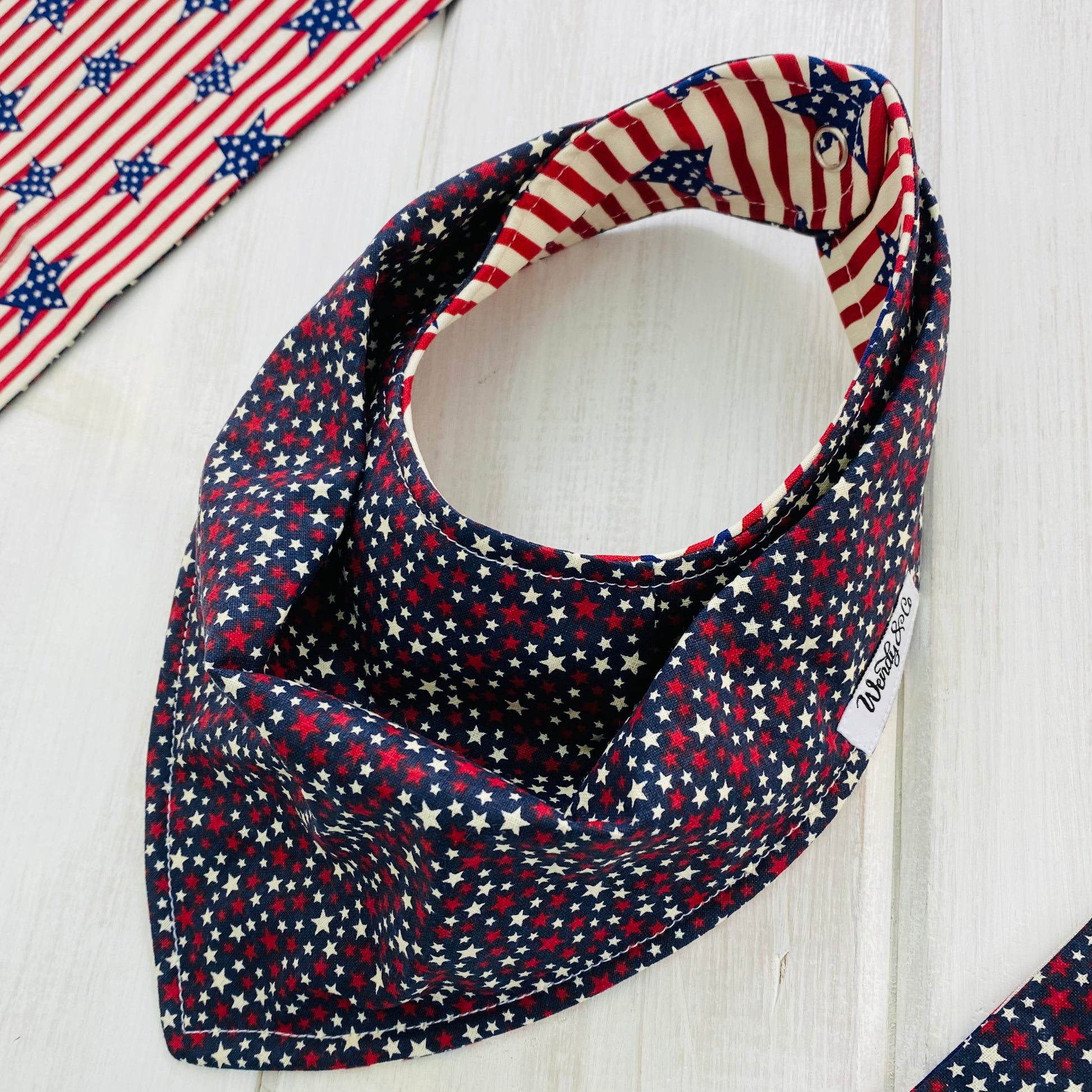 Navy handmade bandana baby bib with red and cream stars, reverse side red and cream stripes with navy stars.
