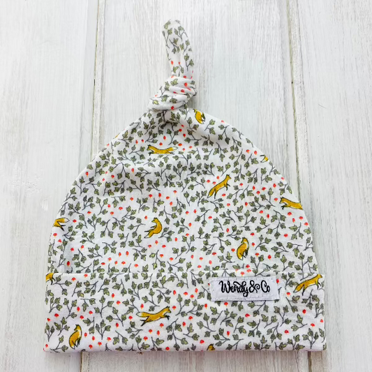 Soft stretchy knit beanie with ivy vines and red flowers and little orange foxes playing in the leaves.