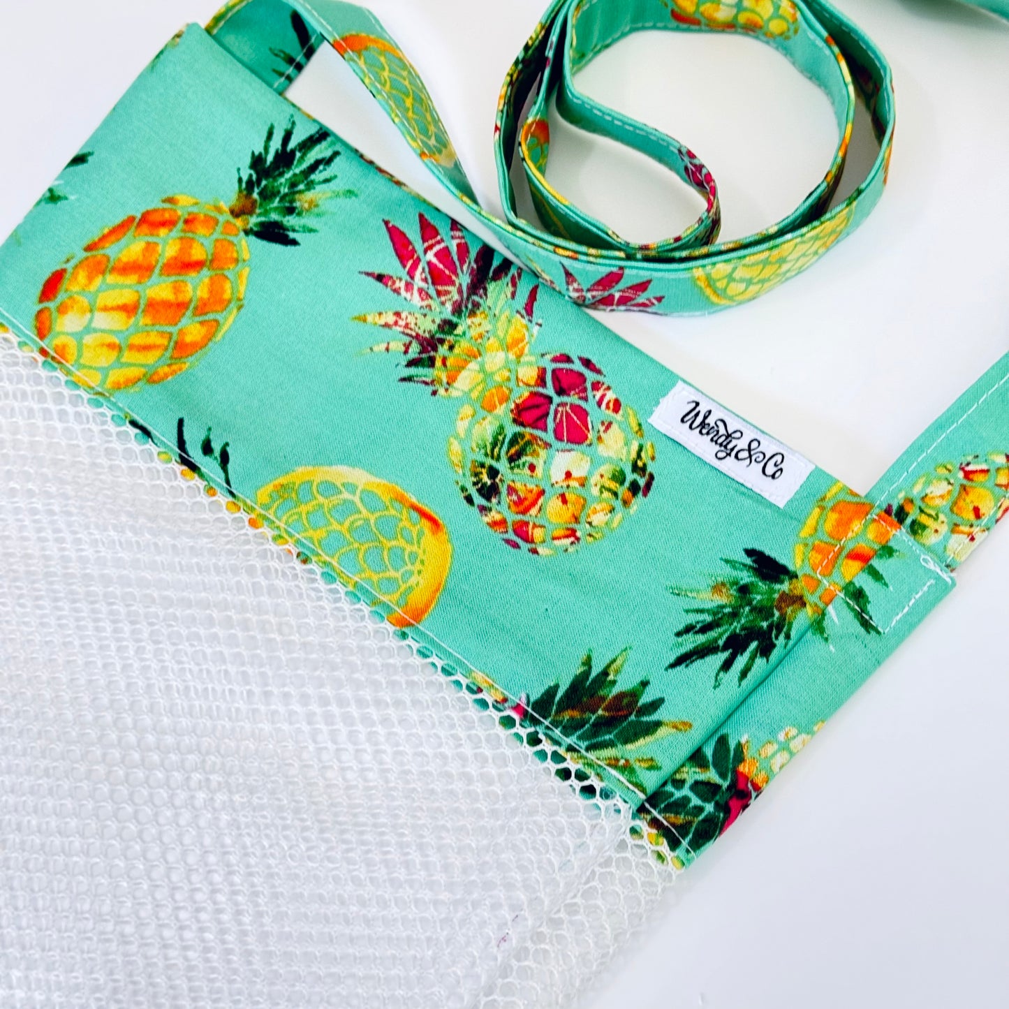 Write Happy pineapples on a teal background seashell bag.