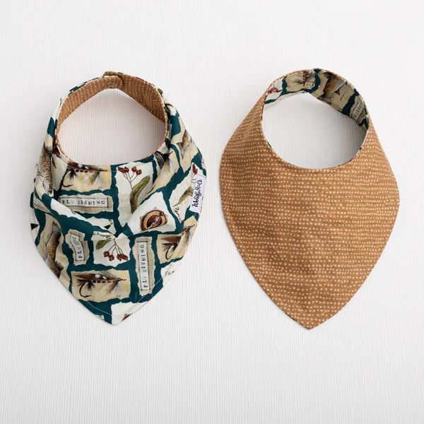 Two reusable bandana-style baby bibs laid flat on a white background. The left bib has a multicolor botanical and trout fish print with teal, beige, and brown tones, and the right bib is solid tan with small white dots.