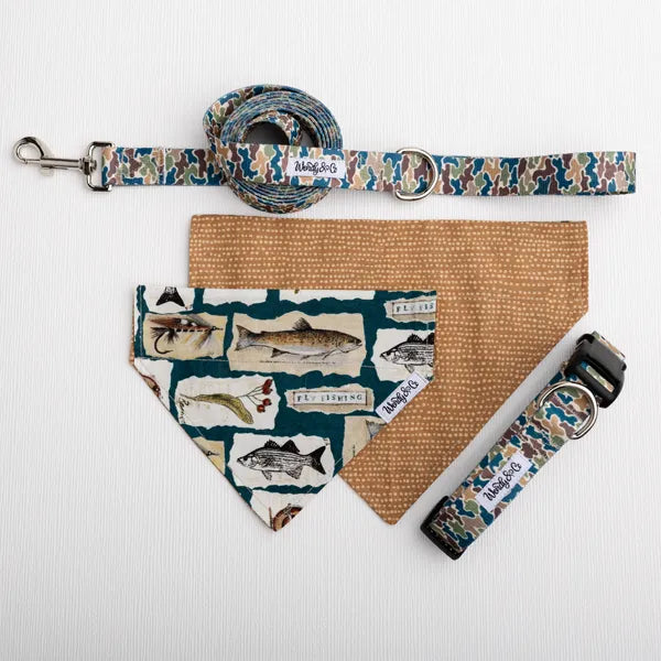 A pet gear set laid flat on a white textured background, including a camouflage-patterned leash, matching collar, tan bandana, and a fish-print bandana. The collars show the brand name Wendy&Co.