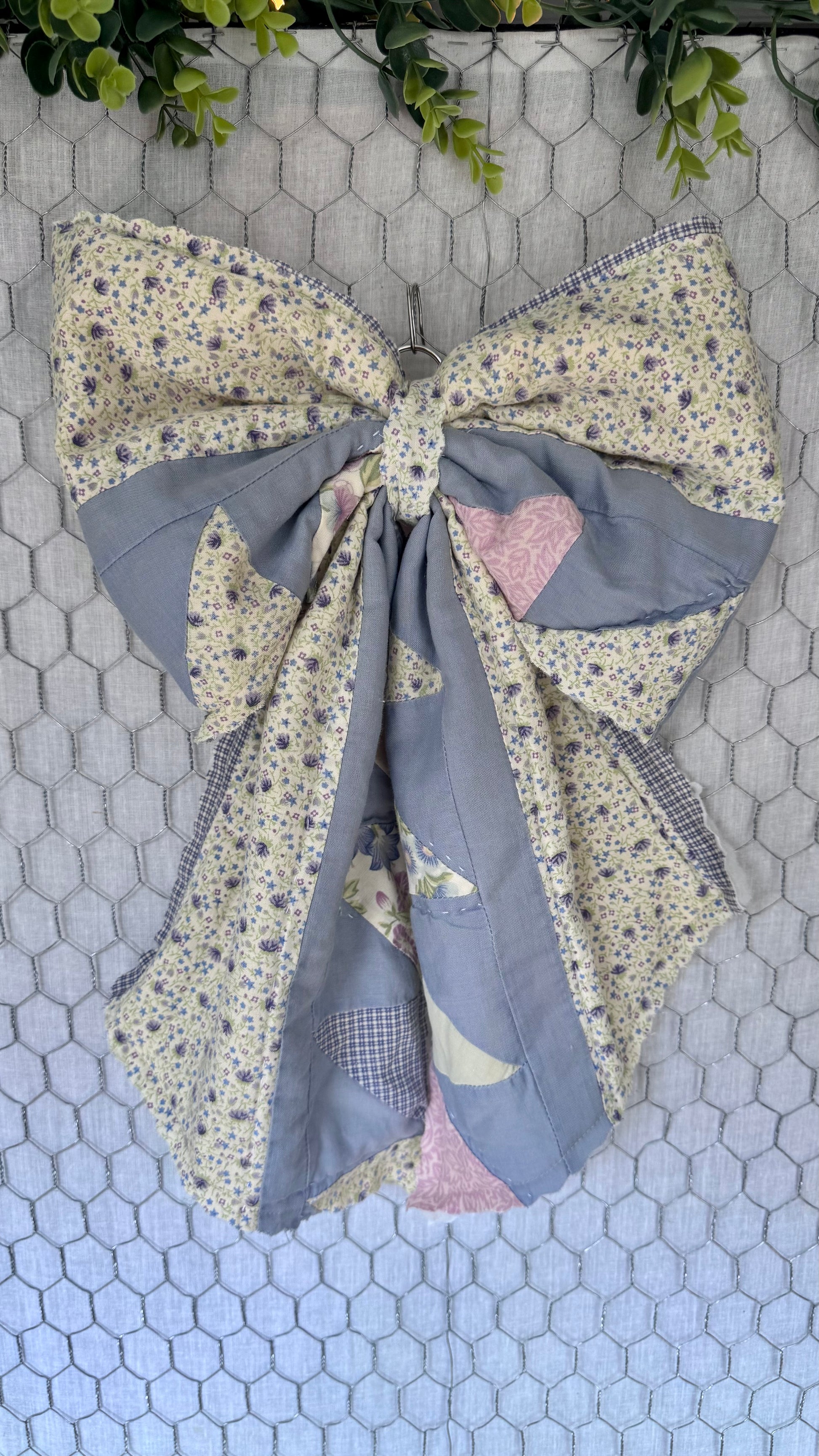 Large fabric bow with floral and patchwork patterns on a hexagonal tile background