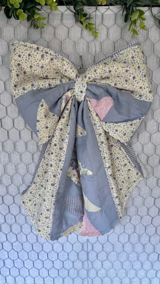 Large fabric bow with floral and patchwork patterns on a hexagonal tile background