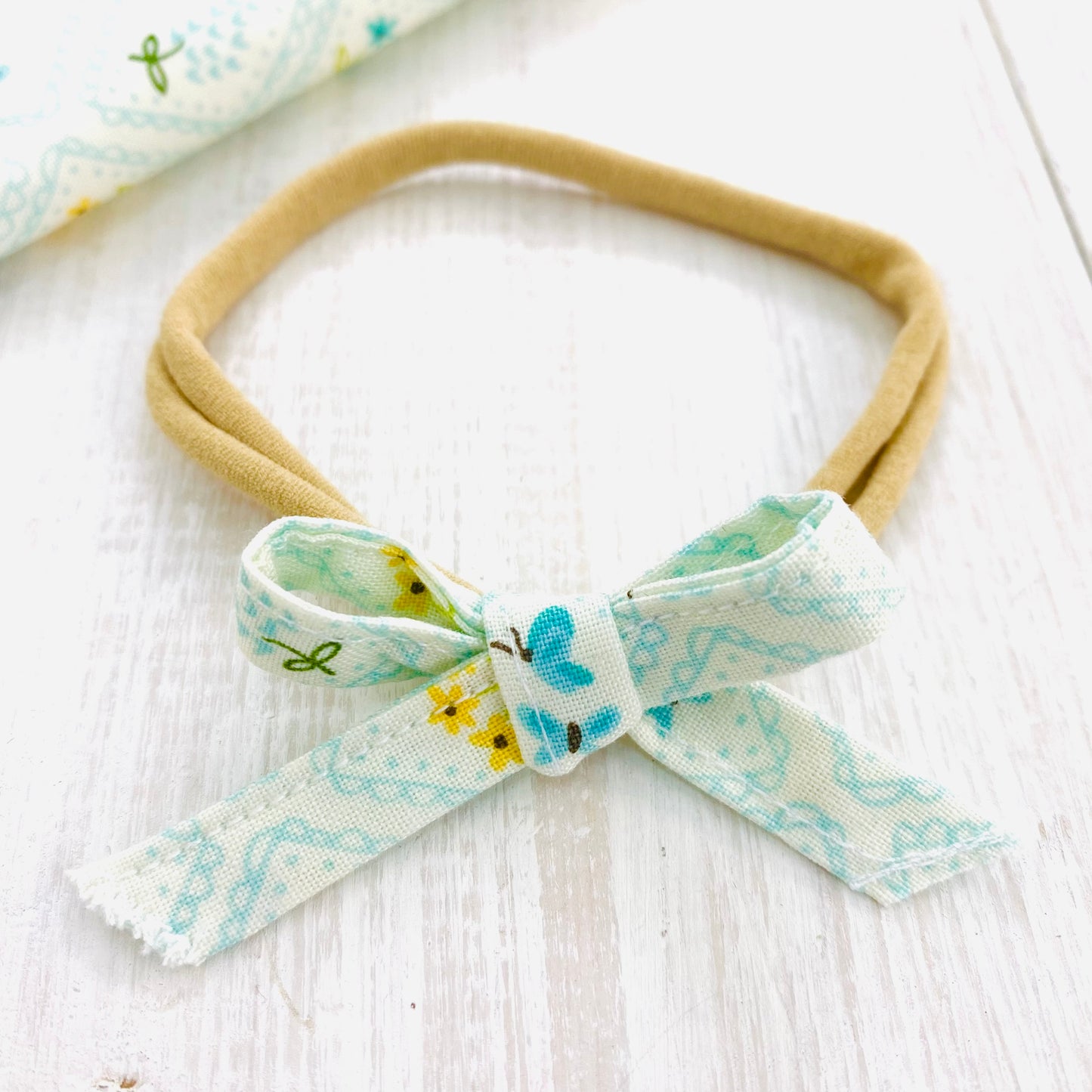 Hand tied baby bow headband in blue floral with butterfly.