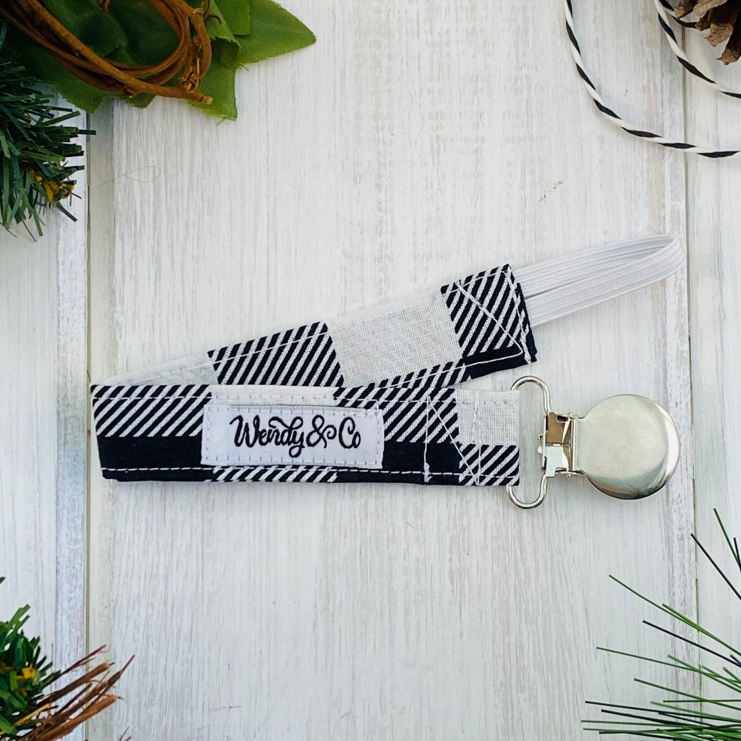 Fabric and metal Pacifier clip in classic black and white buffalo check.