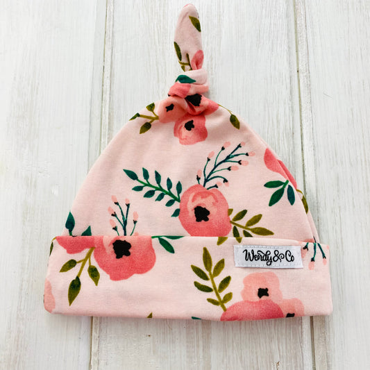 Peach floral newborn beanie with top knot.