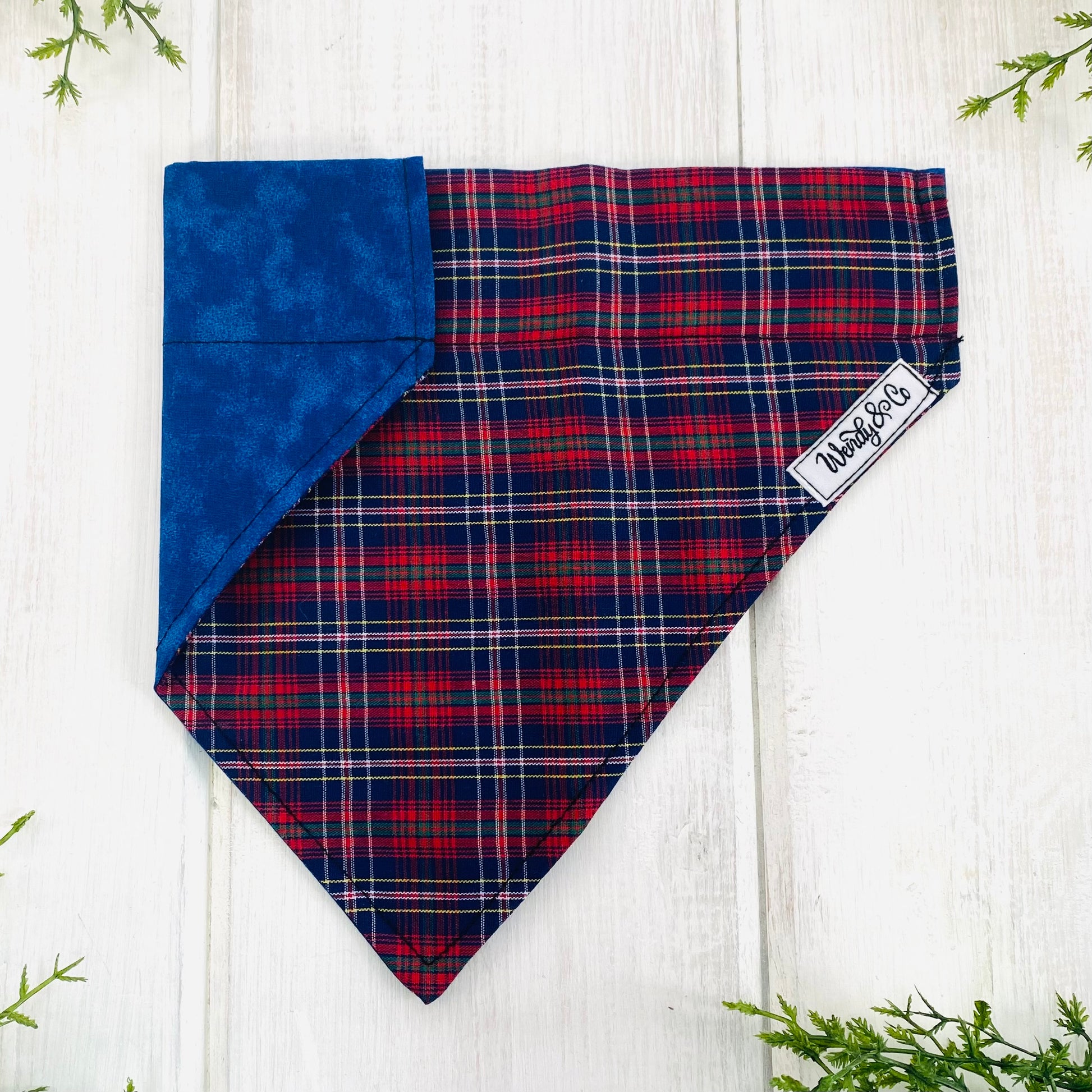 Reversible dog bandana in navy and red plaid with navy reverse.