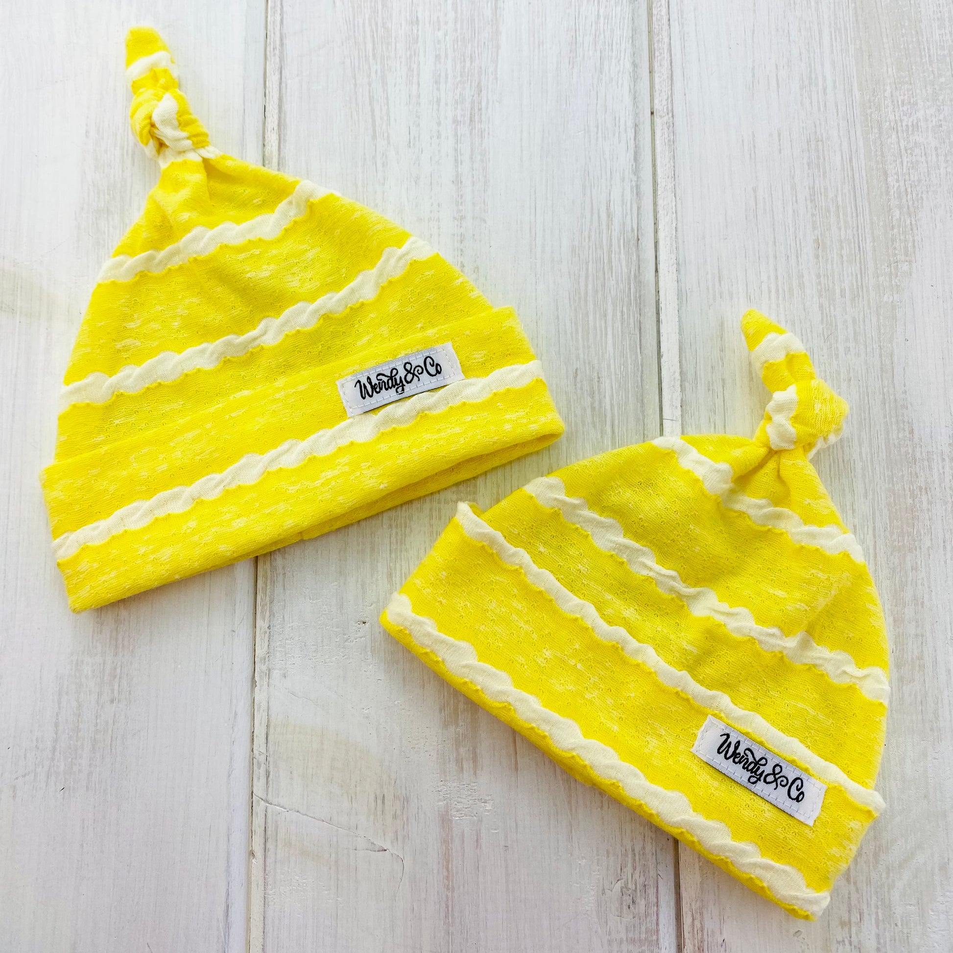 Bright yellow infant beanie with white textured stripe.