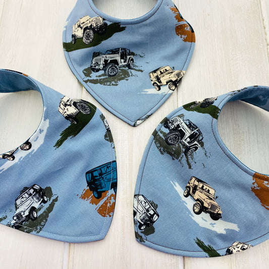 Reversible bib for baby with 4-wheeling jeep scenes.