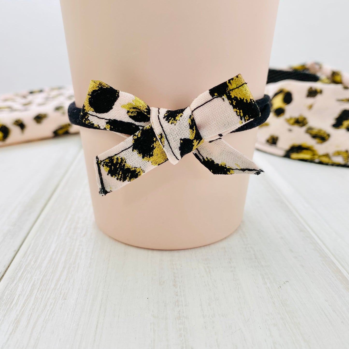 Handtied bow on stretchy headband, blush pink cheetah print fabric on black headband.