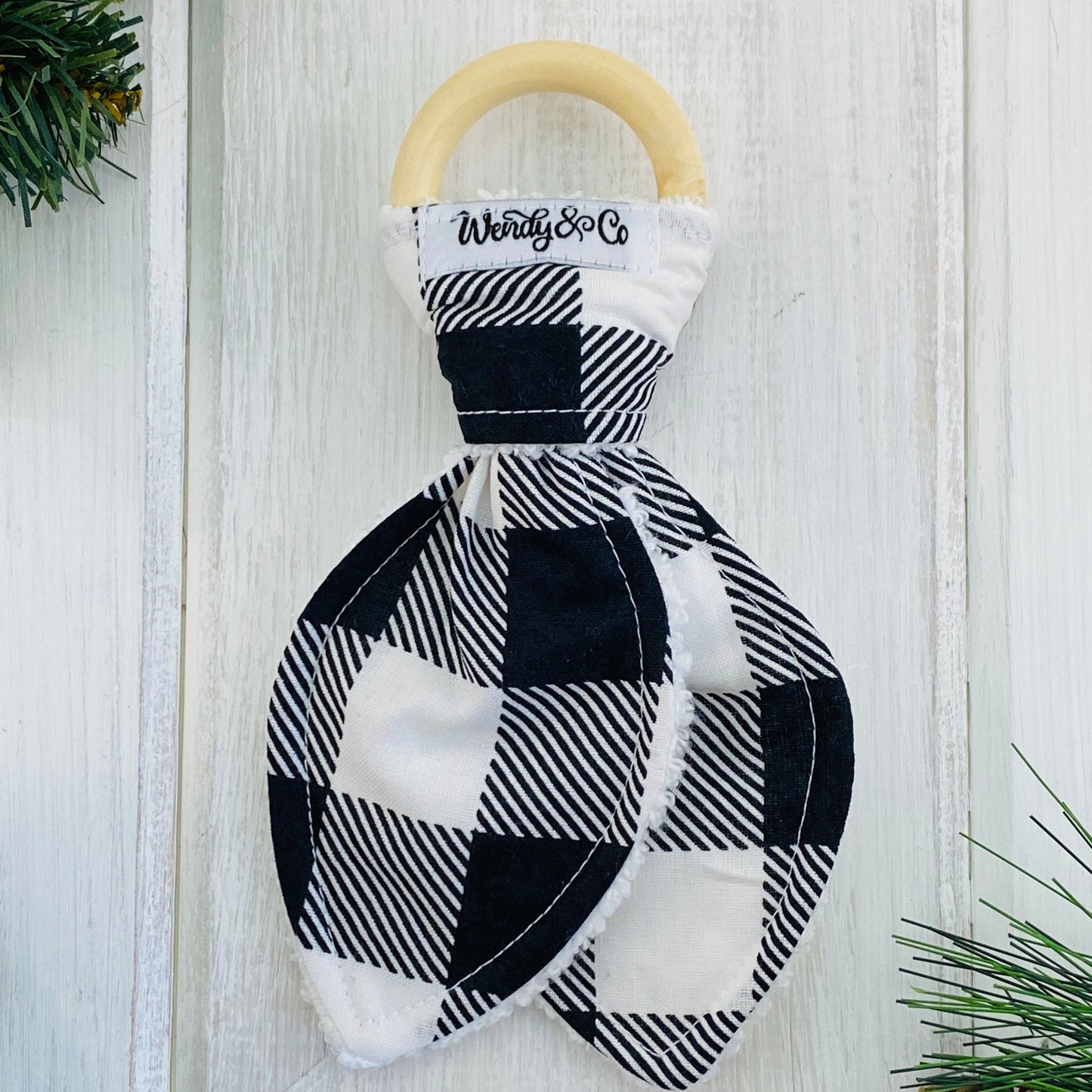 Handmade bunny ear teether, natural wood and fabric shown in black and white buffalo check.