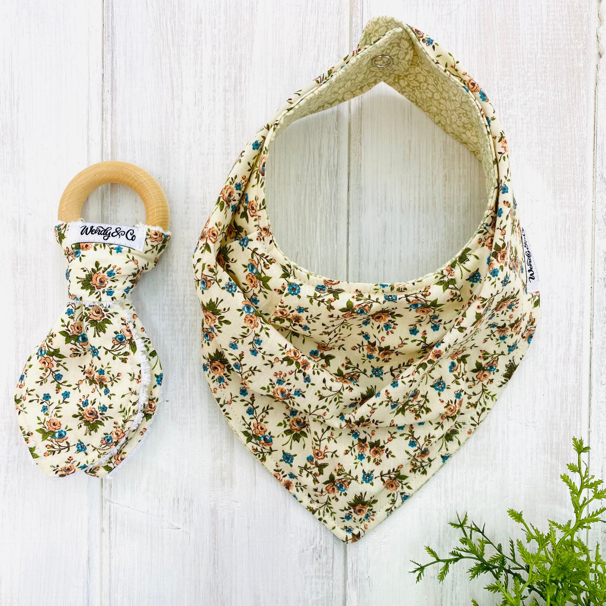 wood and fabric bunny ear teether  and baby bandana bib in vintage floral with rust, blue and olive flowers on cream background.