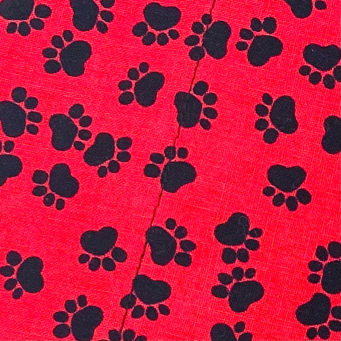 Close up of red fabric with black heart paw prints.