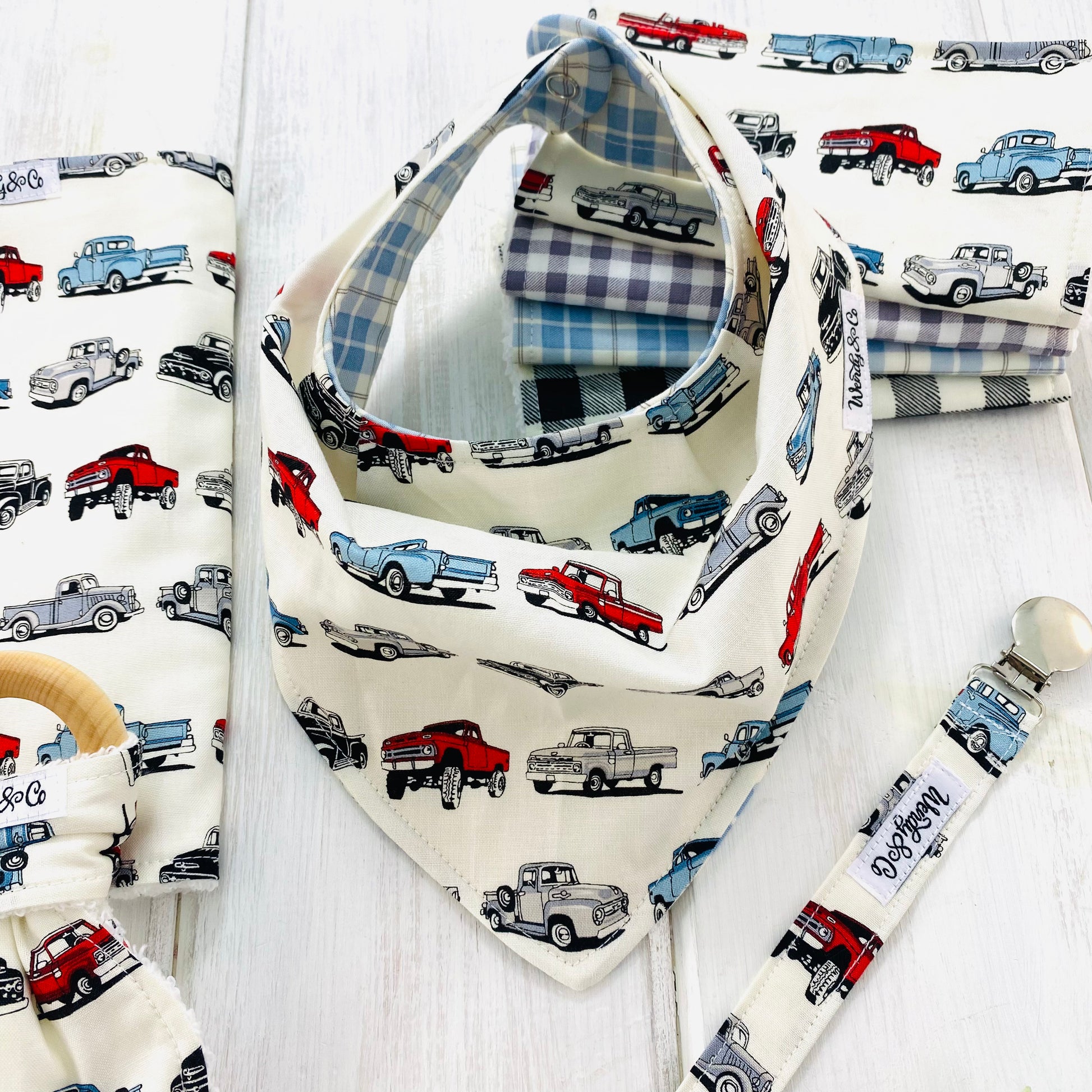 Reversible baby bib with blue plaid on one side and classic trucks on the other side.