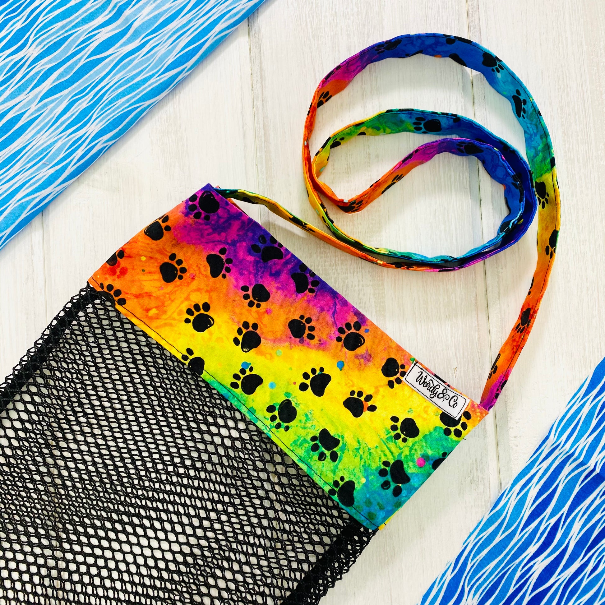Seashell bag with mesh bottom for rinsing shells, in bright tie-dye pattern with black paw prints.
