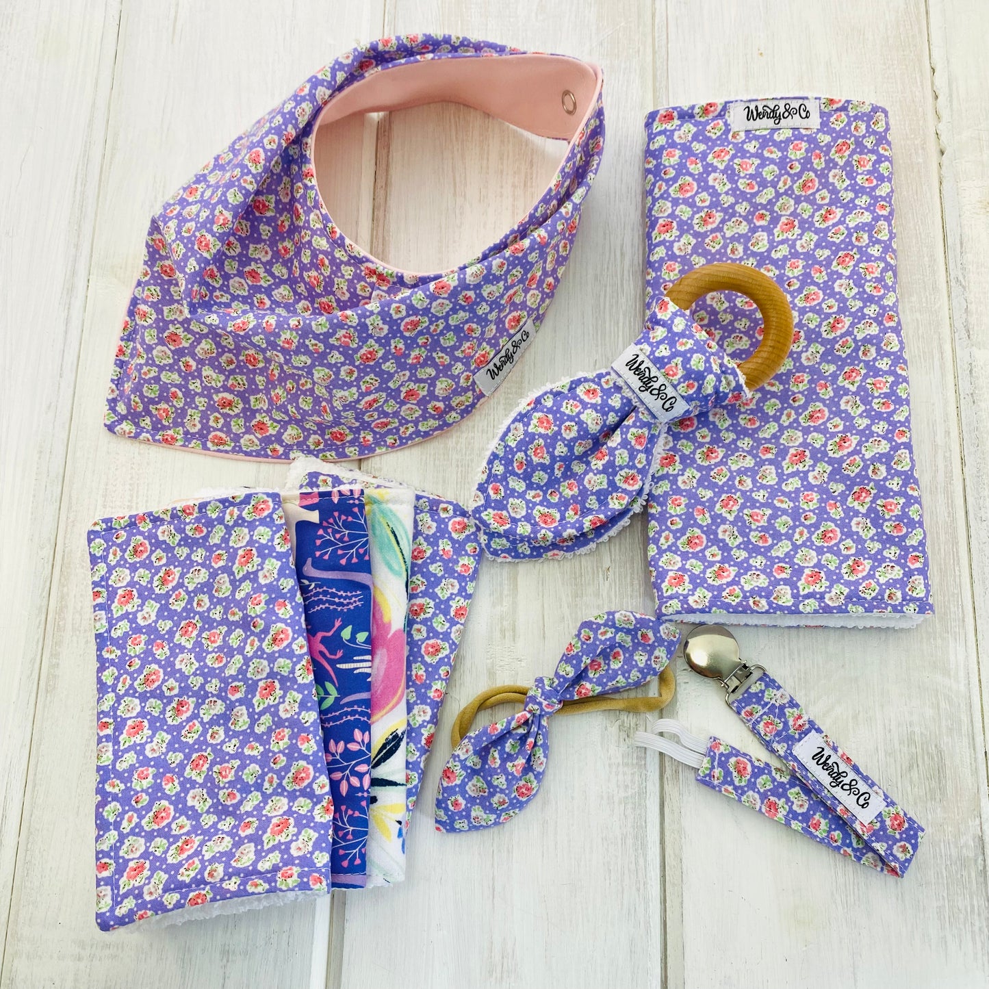 Baby girl gift set in lilac lavender purple with pink flowers. Bandana bib, teether, burp cloth, washing cloths, headband and paci clip.