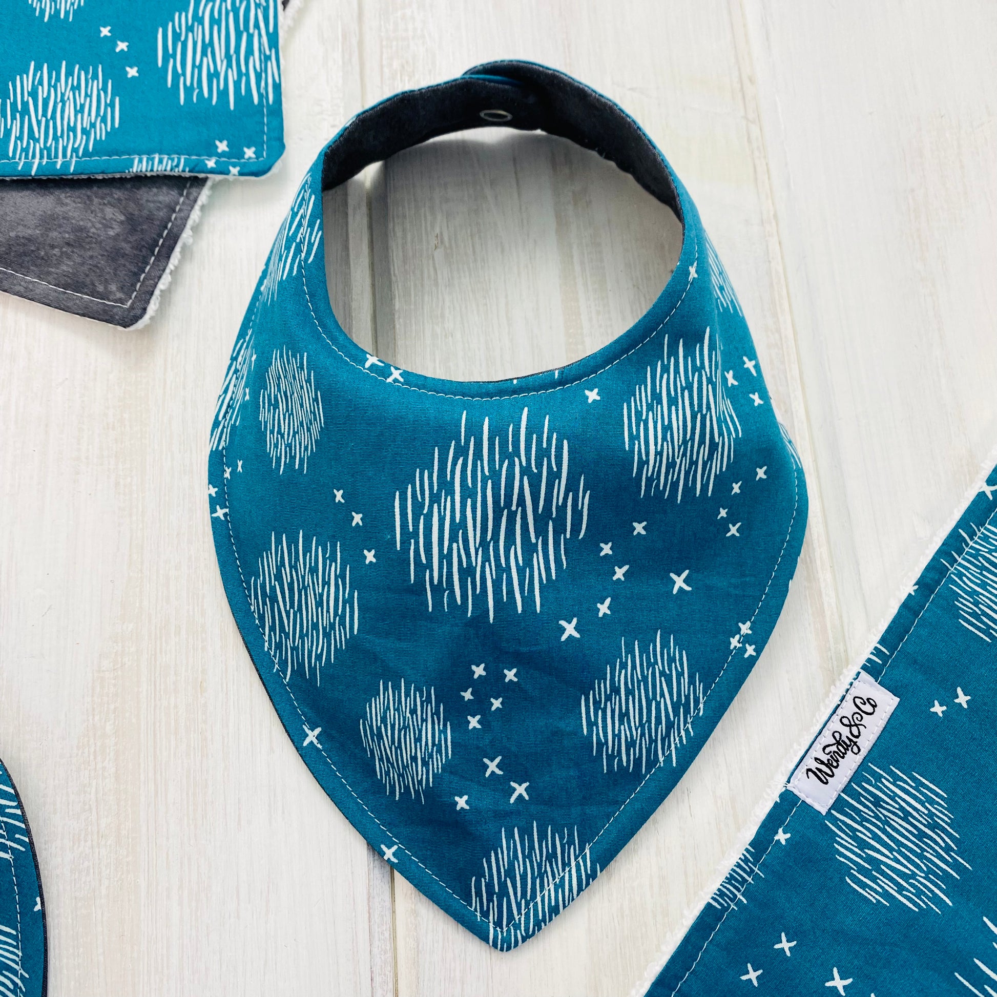 Neutral baby bib in teal cross and hatch print fabric.