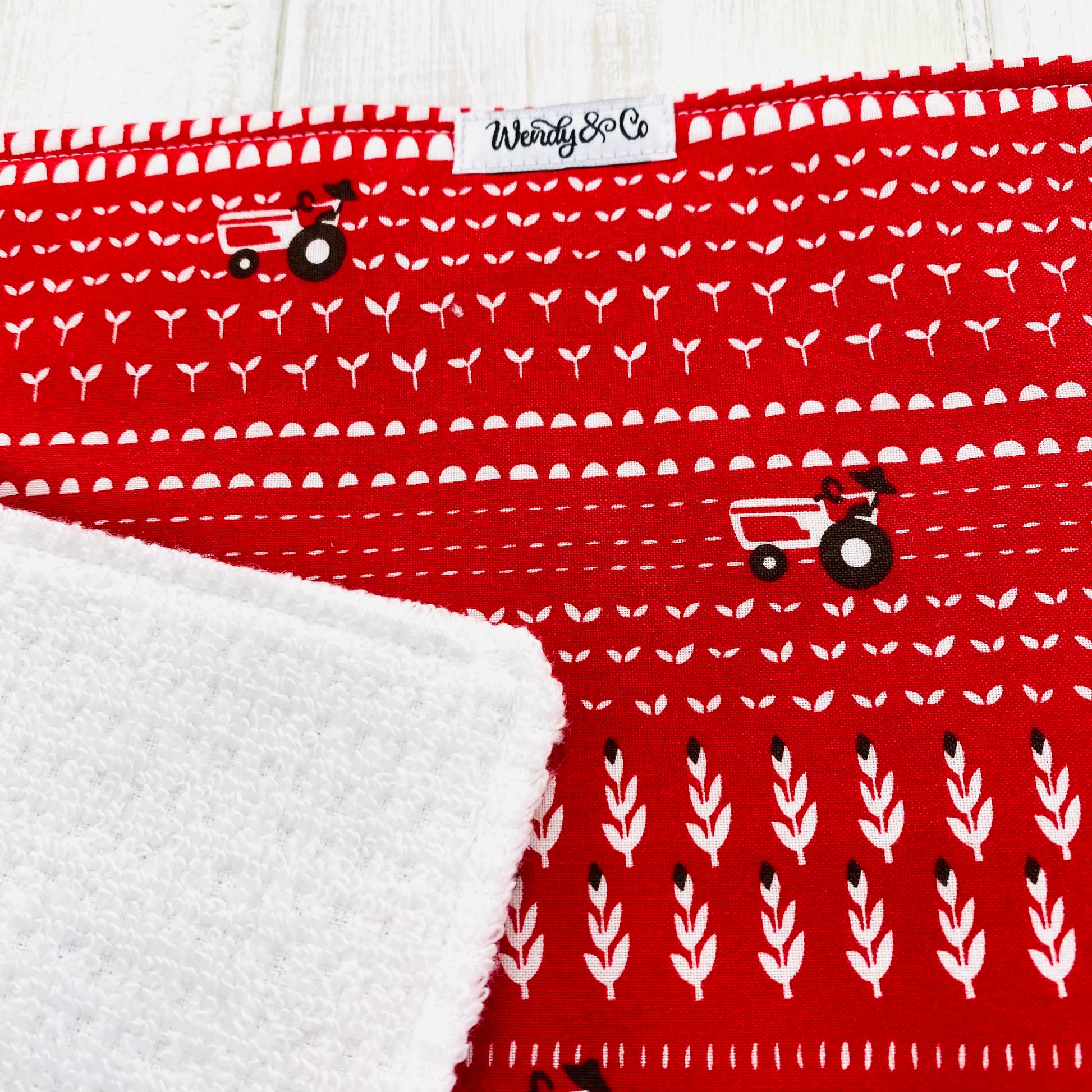 Baby burp cloth or drool rag in red print with white tractors and fields.