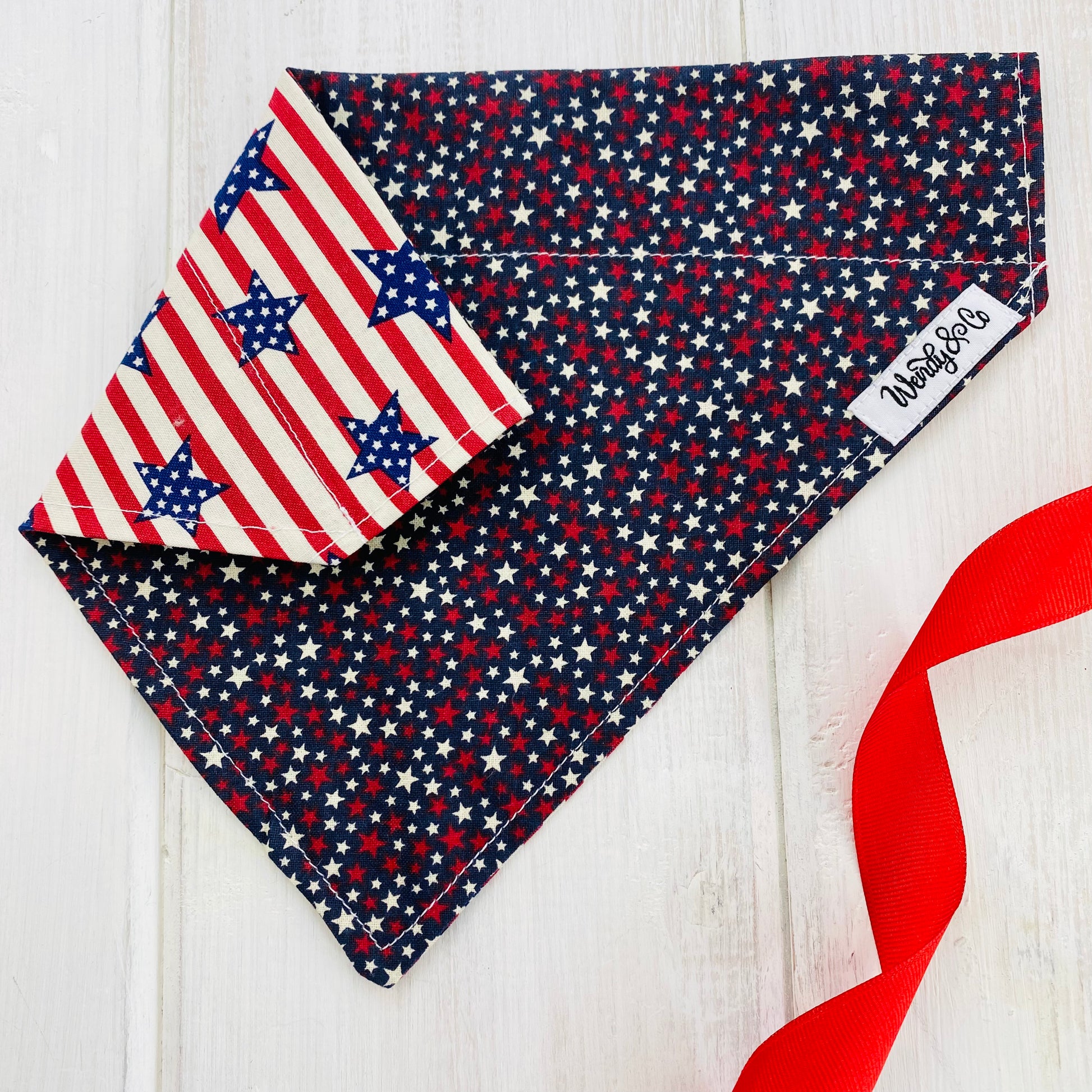 reversible handmade dog bandana, navy fabric with red and cream stars, reverse side is red and cream stripes with navy stars.