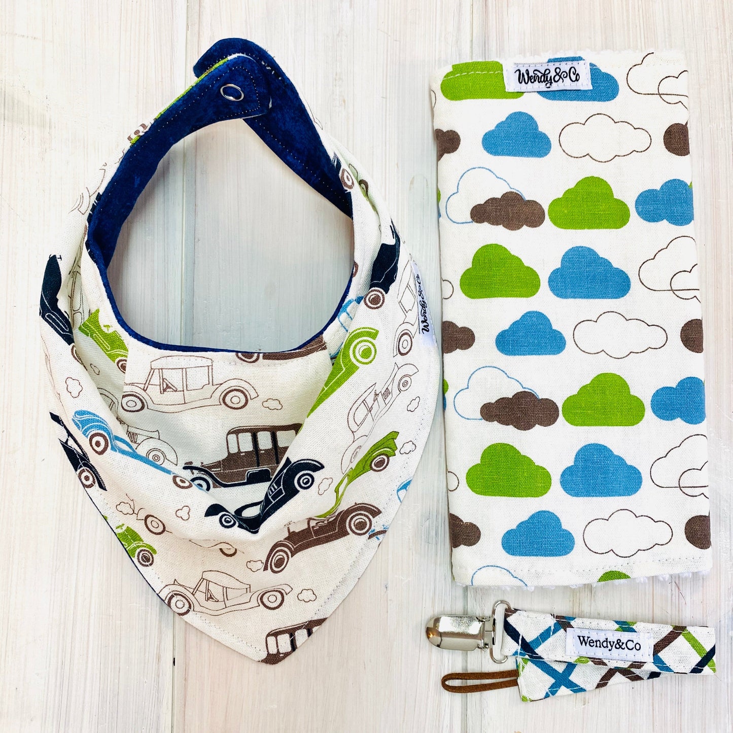 Linen cream burp cloth with clouds in brown, lime, and blue. Shown with coordinating bib and paci clip.