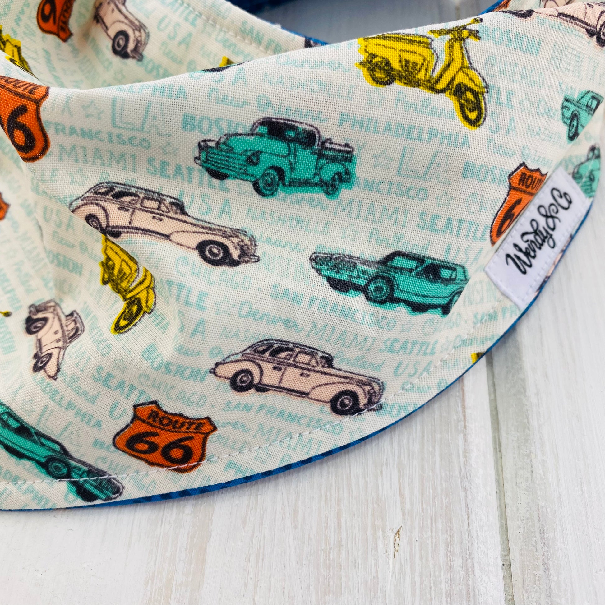 Route 66 fabric with vintage cars in orange, mint and yellow, handmade into a reversible bandana bib.