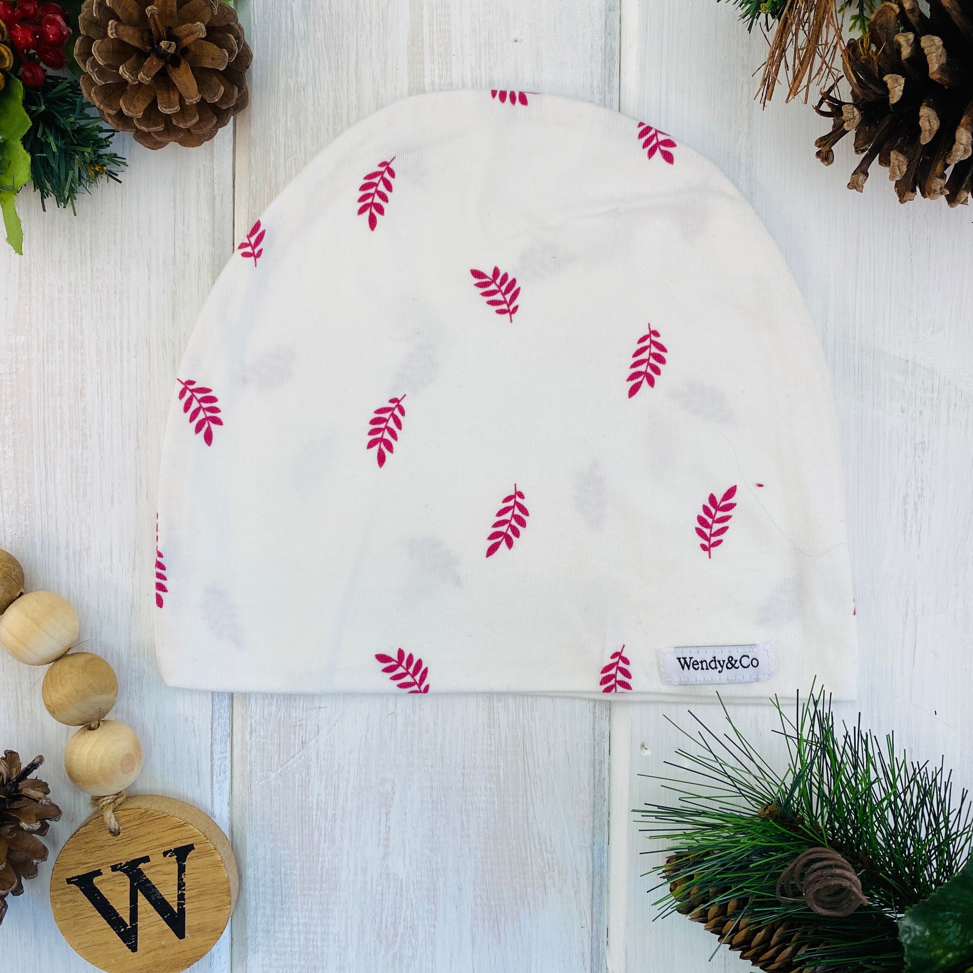 Lightweight cream colored beanie with scattered raspberry color leaves.