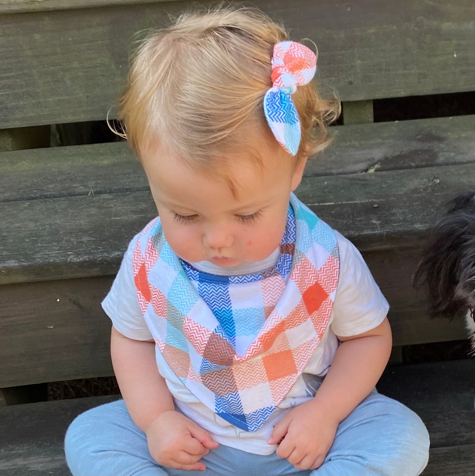 Little girl wearing fall plaid bow and bandana bib.