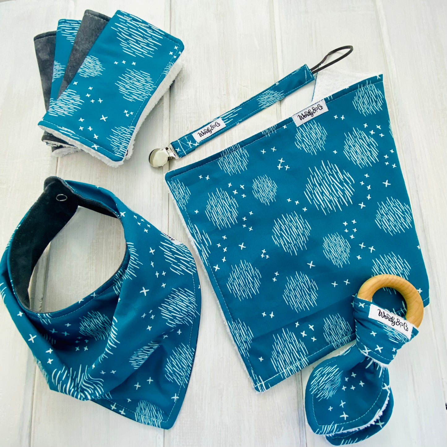 Neutral baby accessories in teal cross and hatch print fabric.
